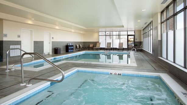 A swimming pool with a metal ladder, lounge chairs, and a seating area with a view of the outdoors. - Hampton Inn & Suites Charles Town (Charles Town)