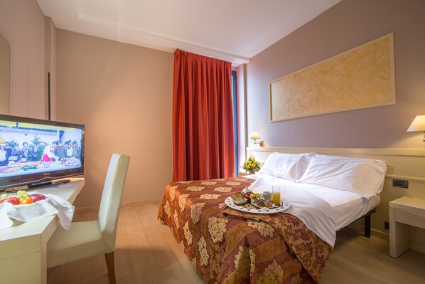 A hotel room with a bed, a desk with a television, and a breakfast tray. - Euro Hotel (Cascina)