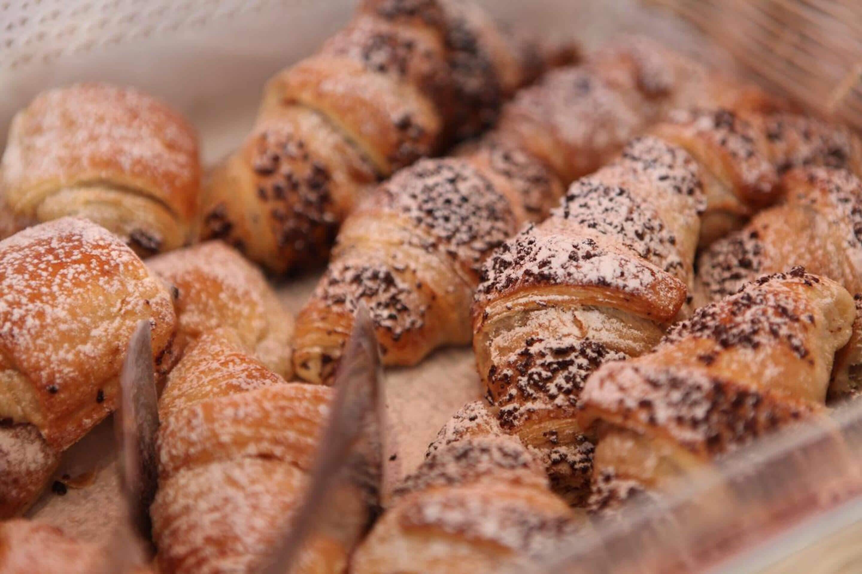 Una cesta con diversos pasteles, incluyendo croissants y otras delicias horneadas.