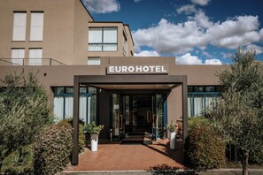 La entrada del Hotel Euro, con un diseño moderno, cuenta con un acceso despejado, plantas en macetas y un camino de ladrillo.