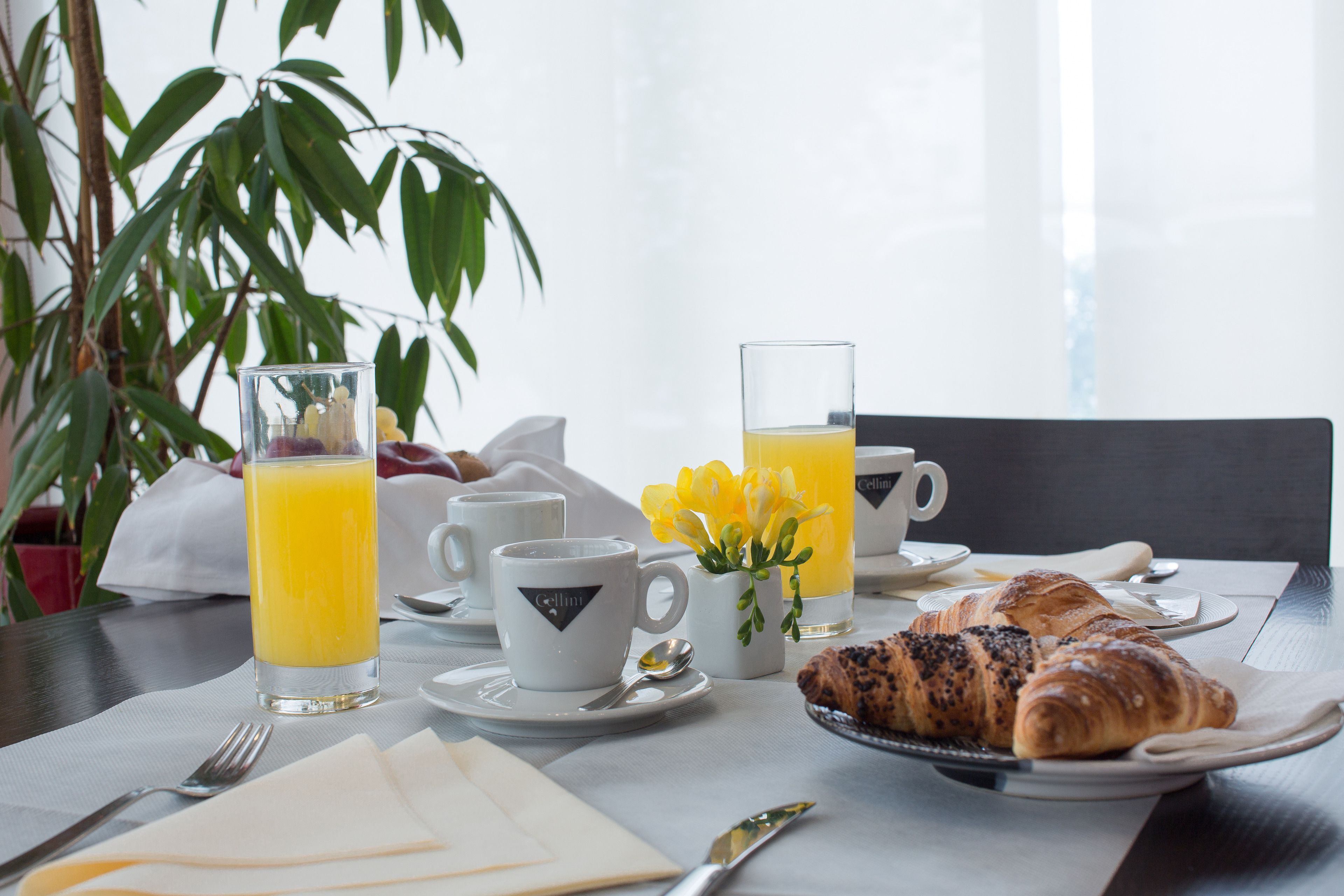 En frukostuppdukning med croissanter, juice och kaffekoppar på ett bord.