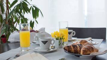 Un desayuno con croissants, jugo y tazas de café sobre una mesa.
