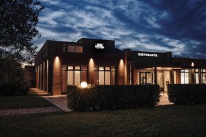 Hotel moderno con restaurante, que destaca por una entrada bien iluminada y un cielo despejado.