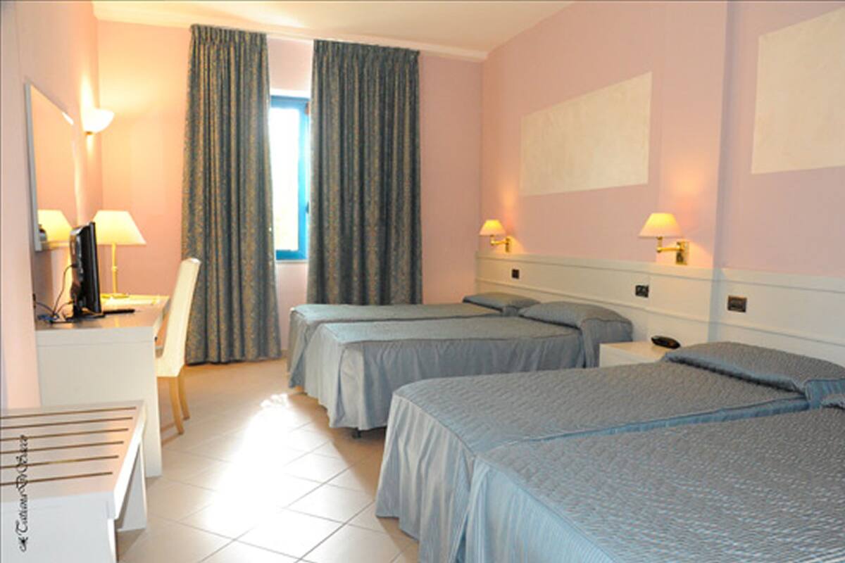 A hotel room with two beds, a desk with a chair, a TV, and two bedside lamps.