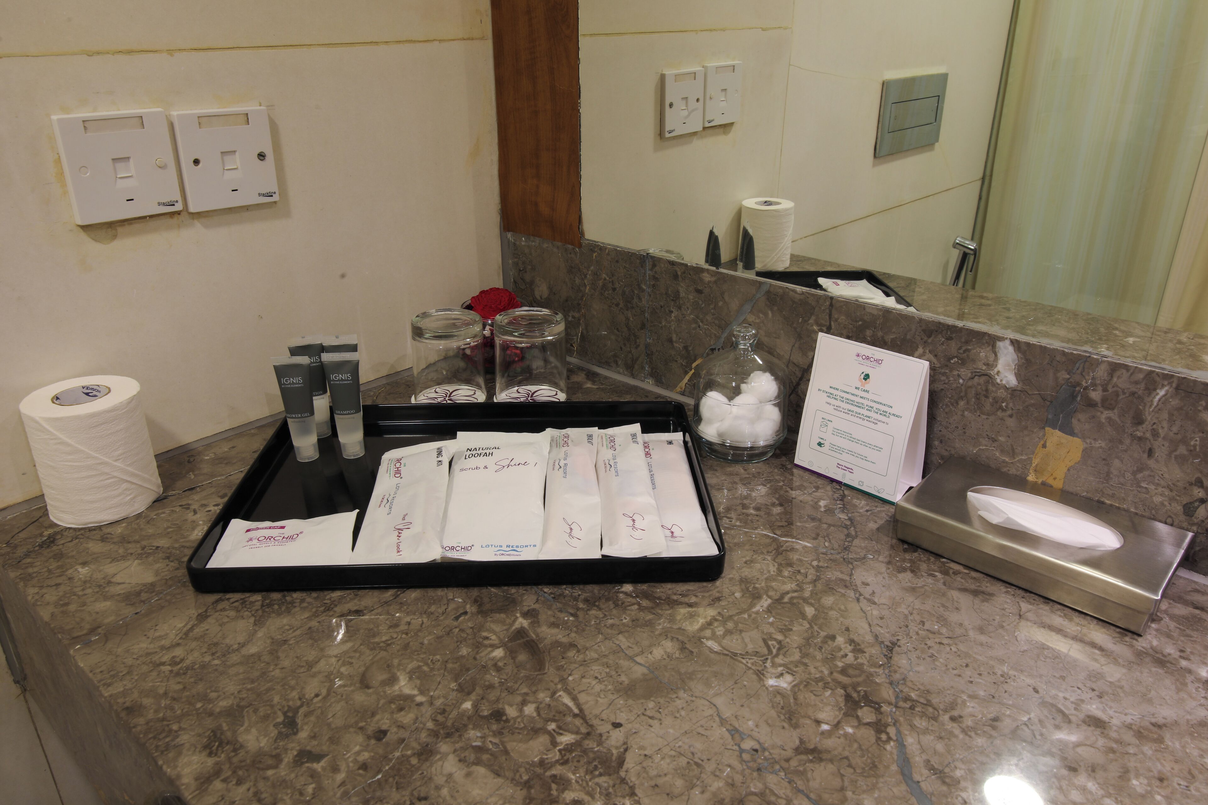 A hotel reception area with a marble counter, toiletries, a tissue box, and a mirror.
