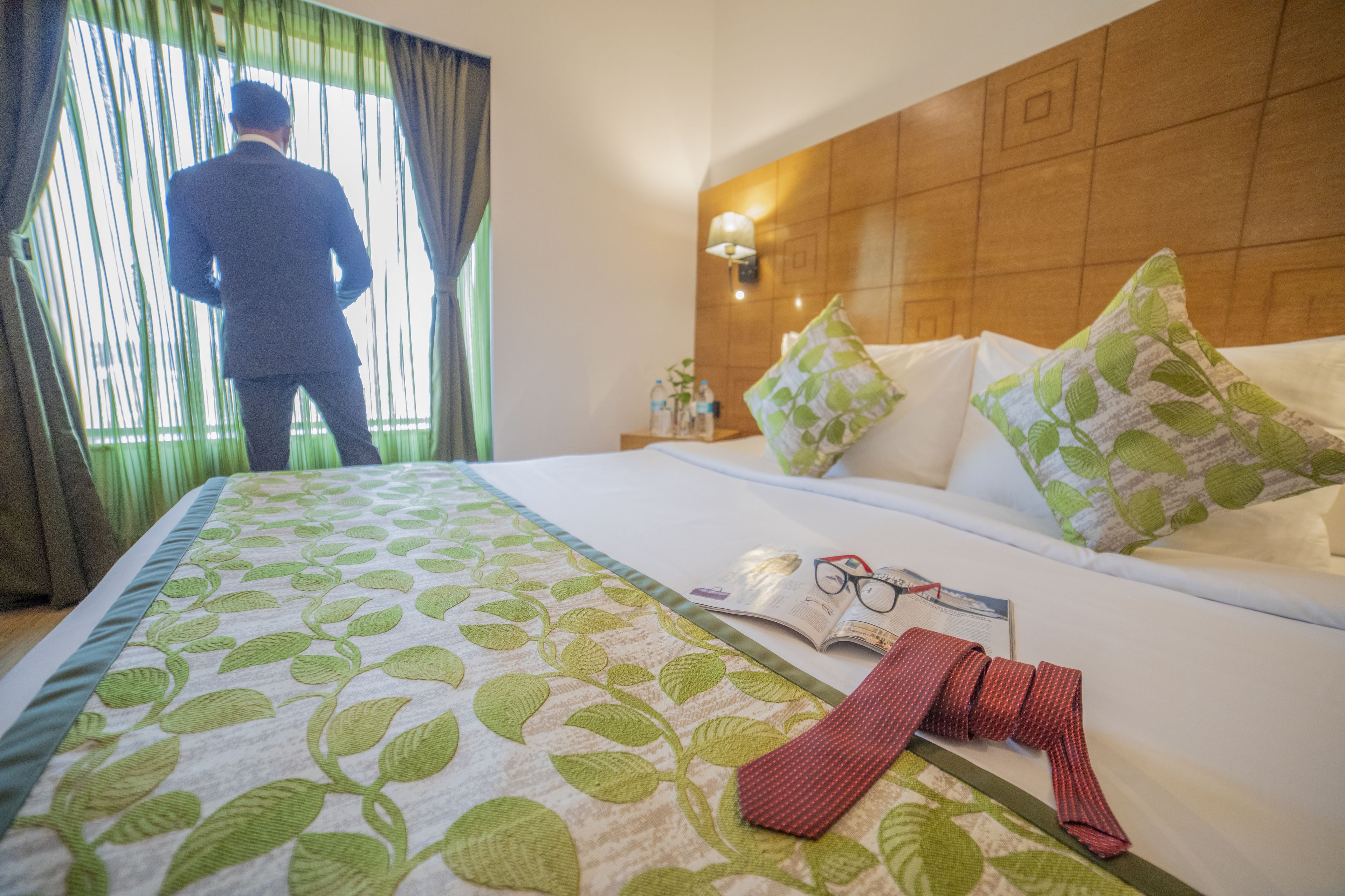 Habitación de hotel con una cama, almohadas, una corbata roja doblada con cuidado y un libro sobre la cama.
