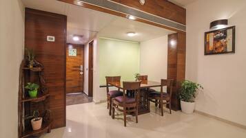 Comedor con una mesa y sillas de madera, una planta en maceta y un cuadro en la pared.