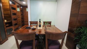A wooden dining table with chairs, a bottle of wine, and a small plant.