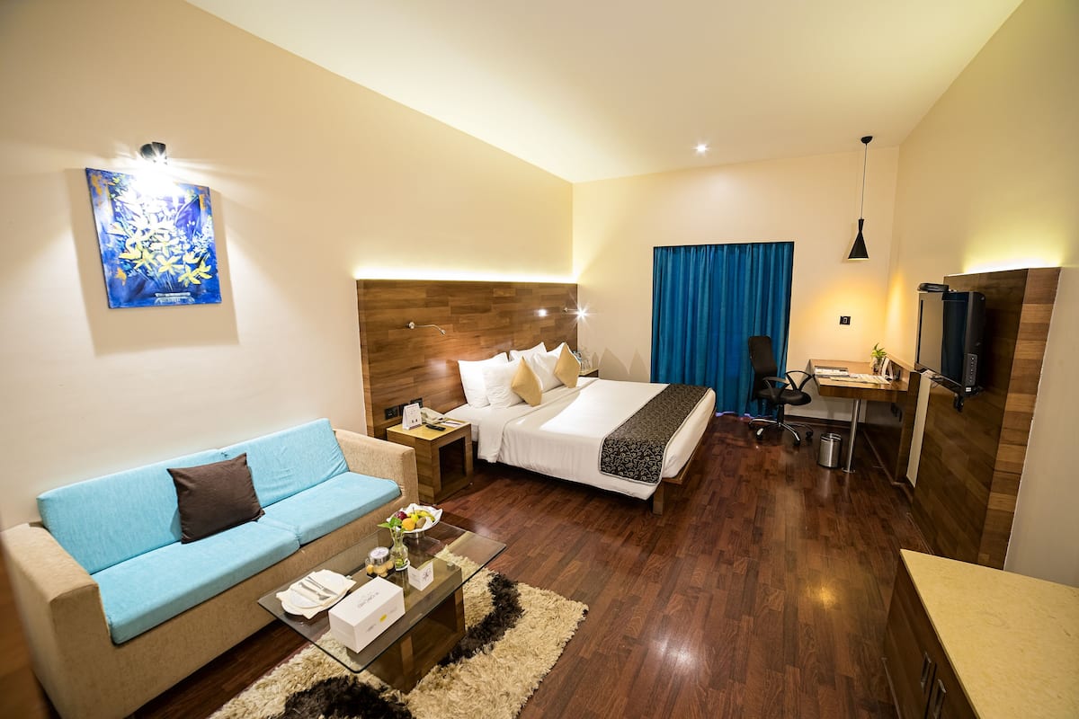Una habitación de hotel moderna con cama, sofá, escritorio y televisor.