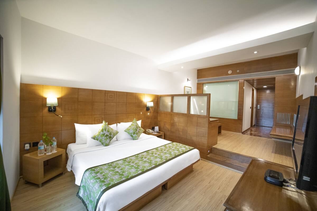 Una habitación de hotel con una cama grande, mesitas de noche, un escritorio y un televisor.
