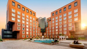 Un edificio moderno con patio, piscina y una estructura de vidrio al fondo.
