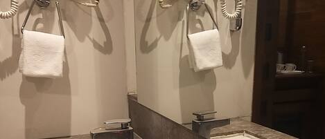 A bathroom with two sinks, a mirror, and a towel rack. There are toiletries on the counter.