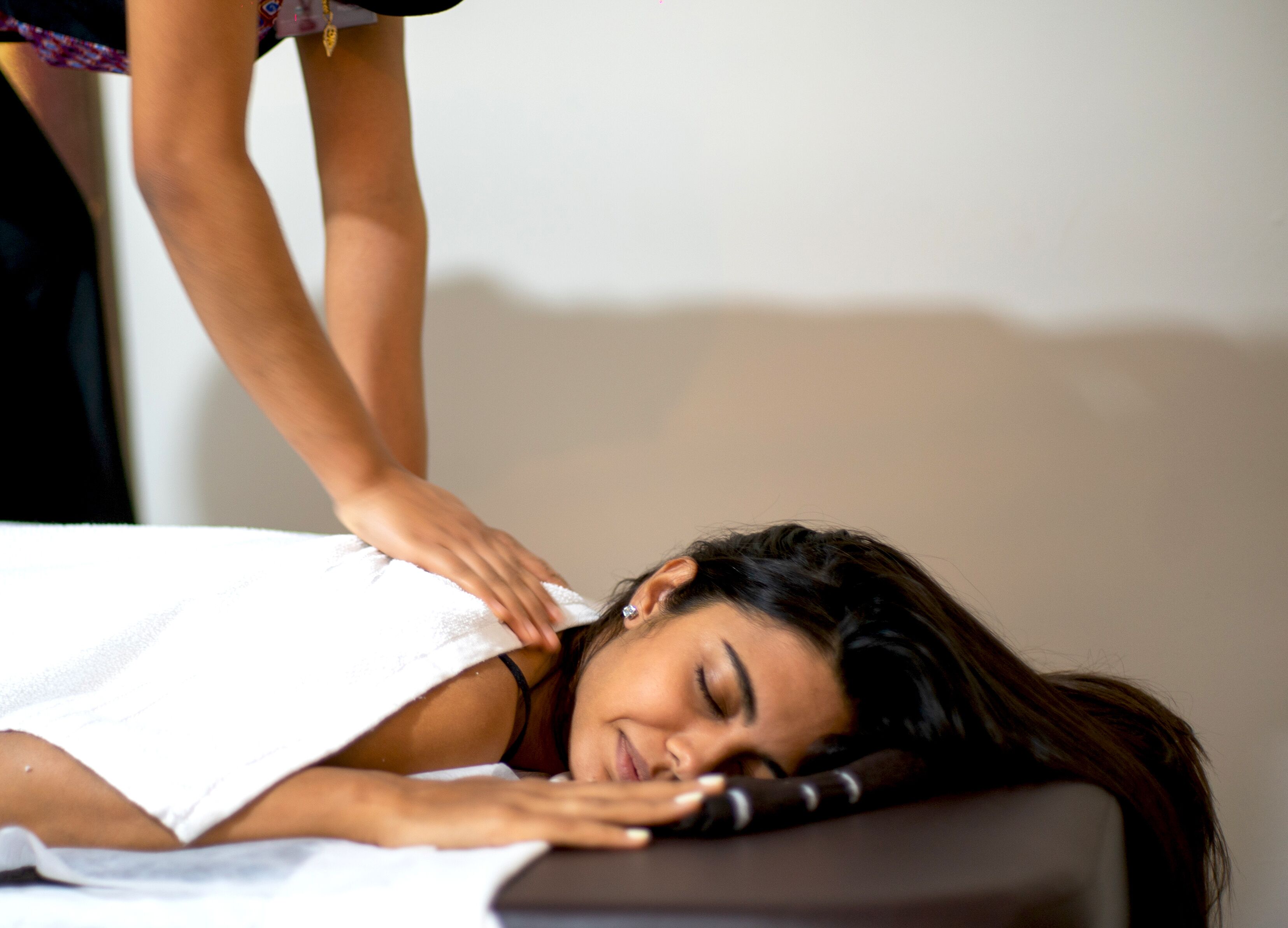 A person lying on a massage table receiving a back massage.