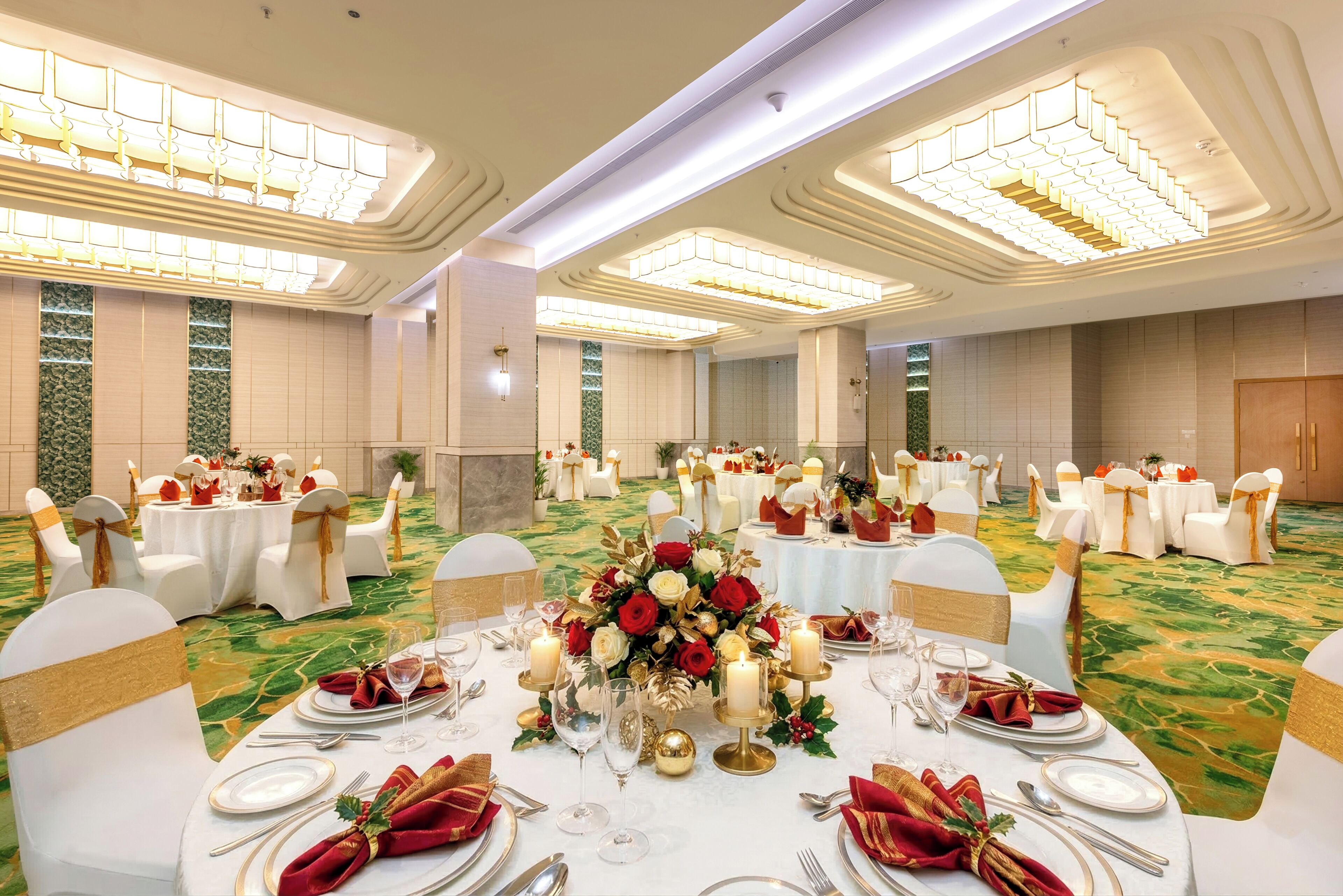 Ein Festsaal mit runden Tischen, weißen Stühlen und floralen Tischdekorationen.