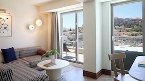 A modern living room with a sofa, a coffee table, and a view of a cityscape through large windows. - A for Athens (Athens)