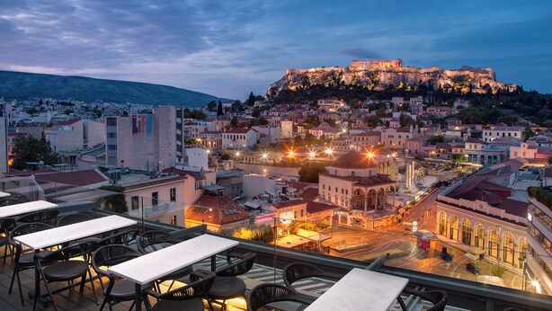 A rooftop terrace with tables and chairs overlooking a historic cityscape with a prominent hilltop fortress. - A for Athens (Athens)