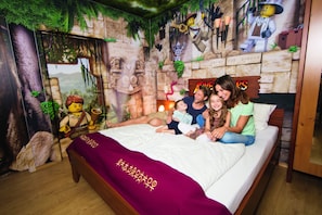 Una habitación con una cama, un mural y una figura de LEGO.