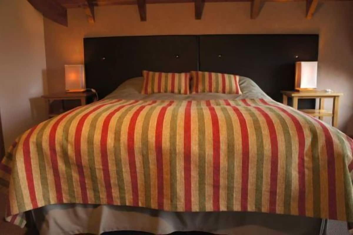 A bed with a striped bedspread, two bedside tables, and a headboard.