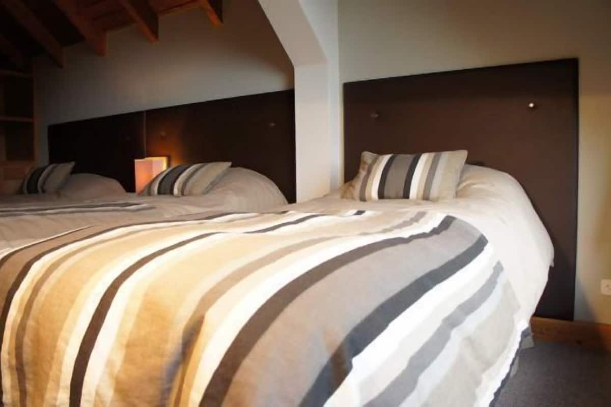 A hotel room with a large bed, a dark headboard, and a bedside lamp.