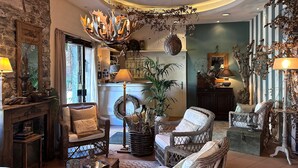A cozy living room with wicker furniture, a fireplace, and a chandelier. - Hotel San Giuseppe (Cernobbio)