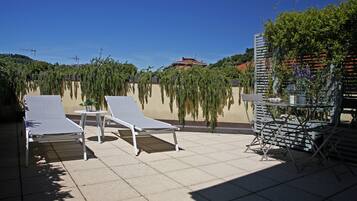 Una terrazza sul tetto con due poltrone e un tavolino, circondata da un muretto e vegetazione.