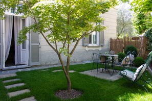 A small backyard with a tree, a patio table, and chairs. - Hotel San Giuseppe (Cernobbio)