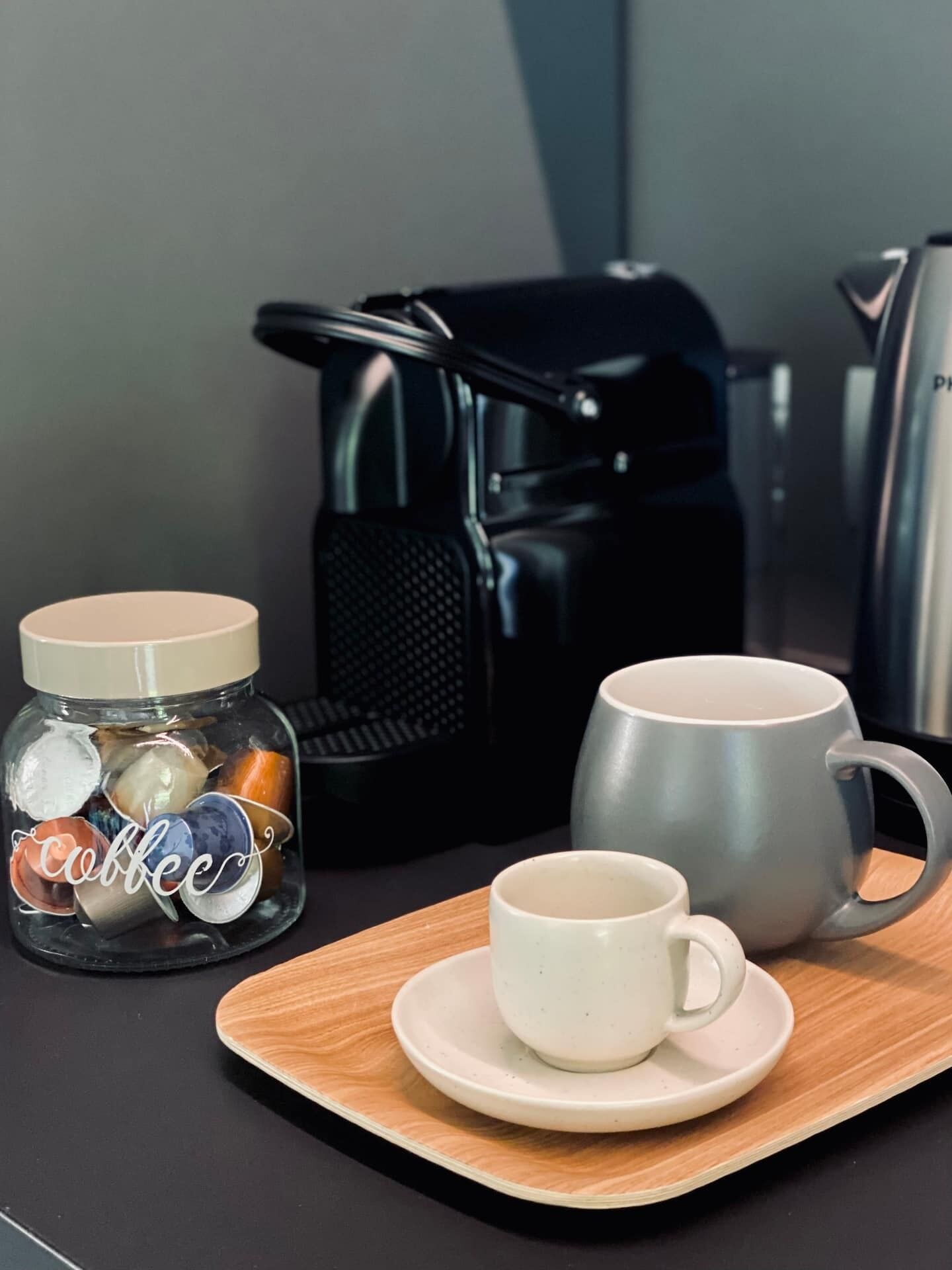A coffee setup with a grinder, a mug, and a container labeled "Coffee" on a wooden tray.