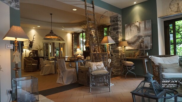 A cozy living room with a stone wall, wooden furniture, and hanging lamps. - Hotel San Giuseppe (Cernobbio)