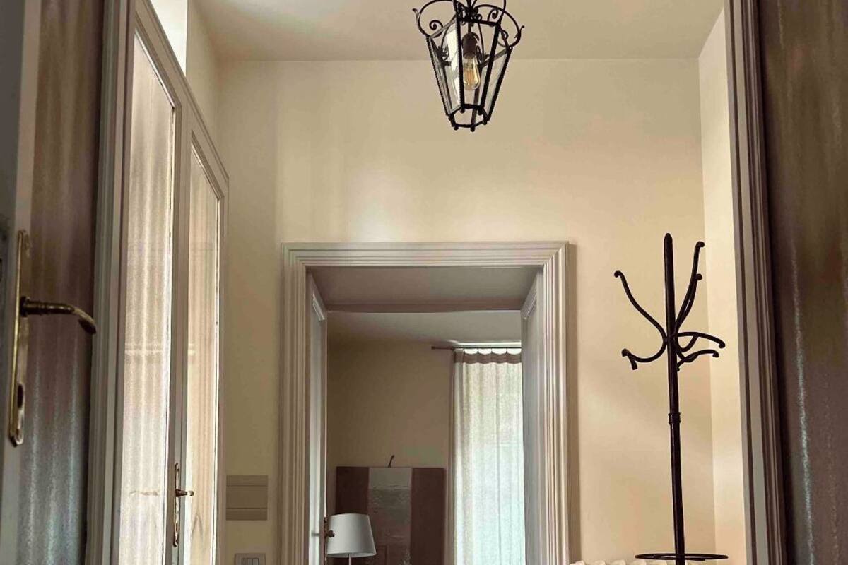 A hallway with patterned flooring, a yellow armchair, a lamp, and a coat rack.