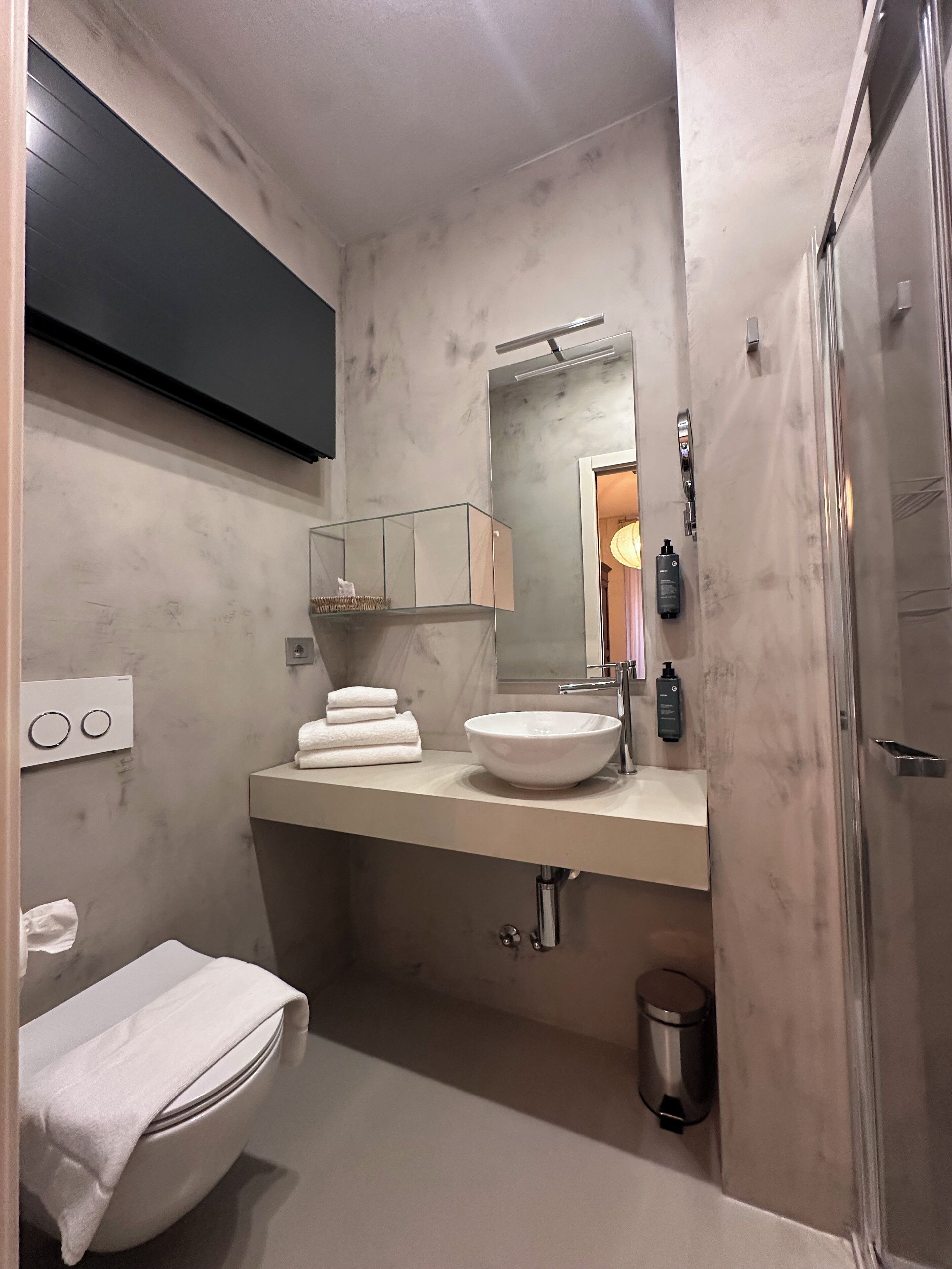 A modern bathroom with a white sink, mirror, and towel rack.