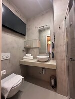 A modern bathroom with a white sink, mirror, and towel rack.