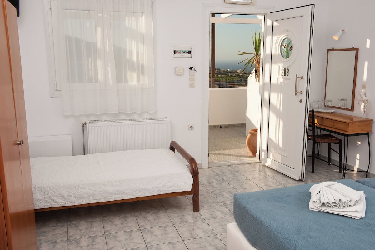Un dormitorio con cama, un baño con espejo y vistas al exterior.