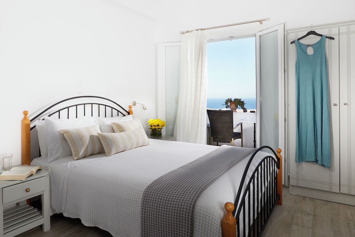 Un dormitorio con cama, mesita de noche y vista al mar.