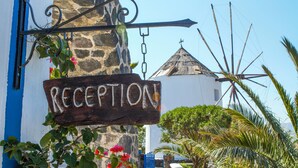 A reception sign with a stone wall and a blue door in the background. - Milos Villas (Santorini)