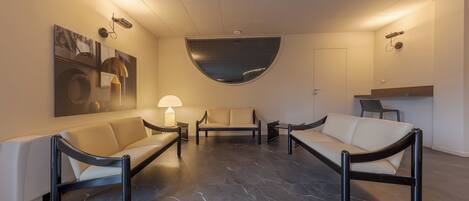 A modern lobby with a sofa, a coffee table, and a lamp.