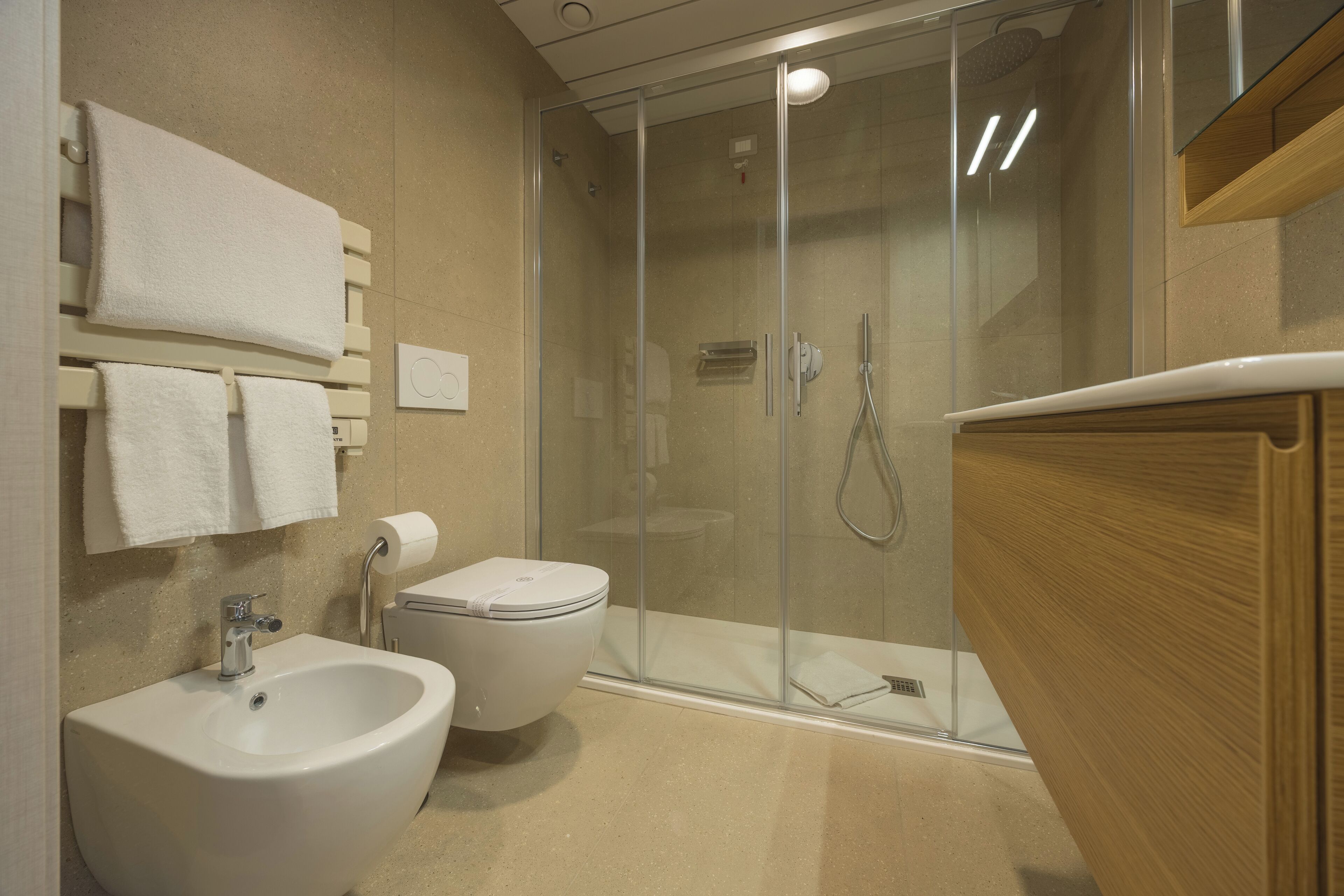 Une salle de bain moderne avec une douche à parois de verre, un bidet, des toilettes et un lavabo.
