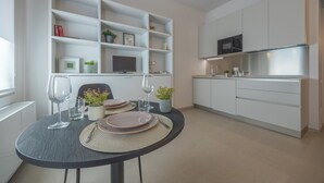 A modern kitchen with white cabinets, a dining table set with plates, glasses, and a vase of flowers. - Centro Siloe Residence Hotel (Milan)