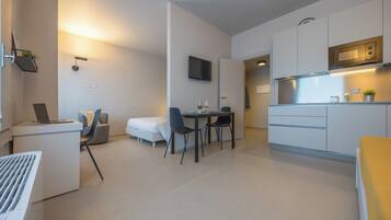Un espacio habitable moderno y compacto con kitchenette, comedor y zona de trabajo.