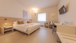 A modern hotel room with a bed, bedside table, lamp, TV, and a desk with a chair. - Centro Siloe Residence Hotel (Milan)