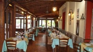 A long dining area with tables set for multiple guests, wooden beams on the ceiling, and a view of the outdoors through large windows. - Agriturismo La Targa (Termini Imerese)
