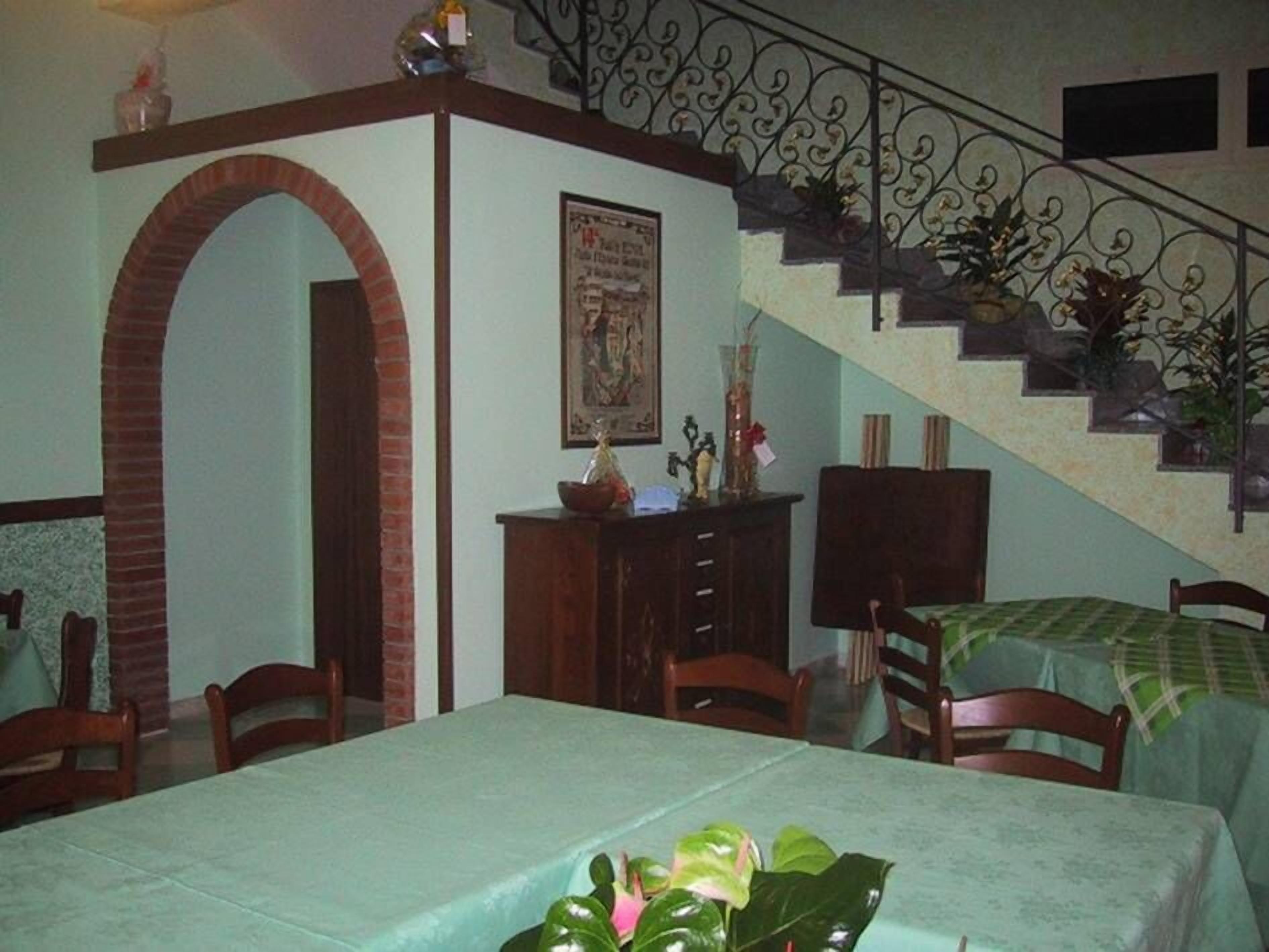 Un coin repas agrémenté d’une arche en briques, d’un escalier avec des rampes en métal et d’une table recouverte d’une nappe verte.