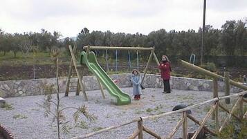Un parque infantil con un tobogán verde y columpios.
