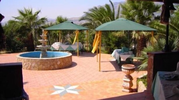 A covered outdoor area with a circular pool, umbrellas, and outdoor seating. - Agriturismo La Targa (Termini Imerese)