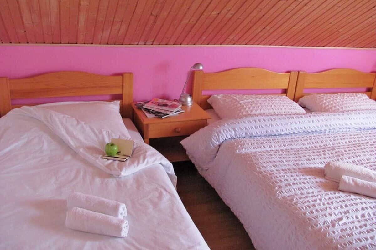 Een slaapkamer met twee eenpersoonsbedden, houten hoofdborden, een nachtkastje met een lamp en een tijdschrift.