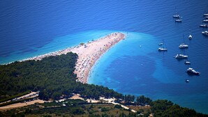 Luchtbeeld van een strand met boten en een bebost gebied.