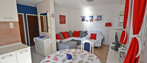 A compact living space with a kitchenette, a dining area, and a seating area with a sofa and chairs.