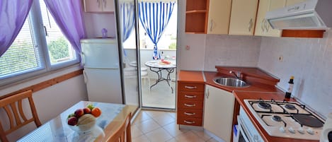 A compact kitchen with a dining table, a refrigerator, a stove, and a sink.