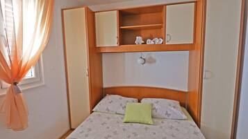 A bedroom with a bed, a nightstand, a wardrobe, and a window with curtains.