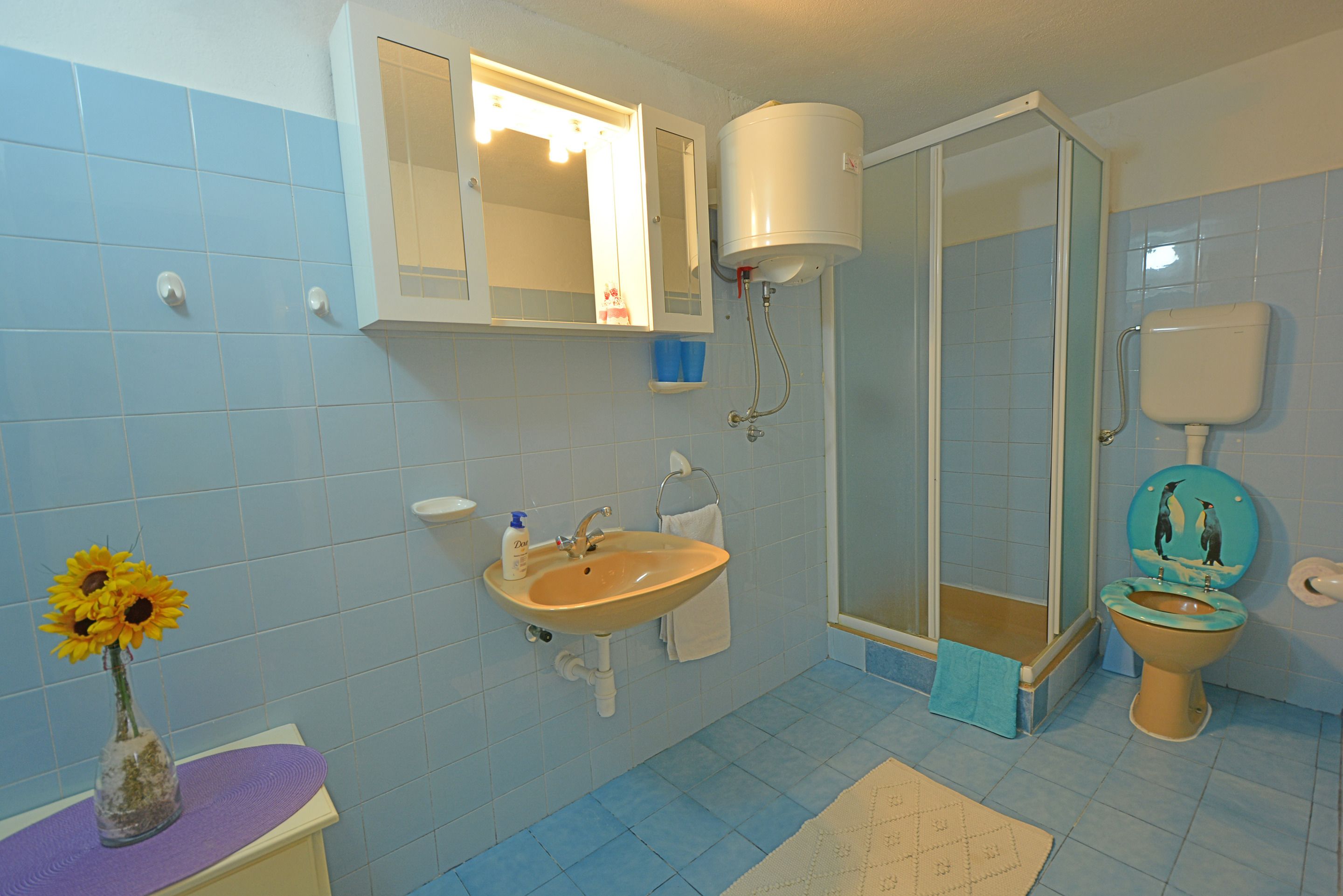 A bathroom with a sink, mirror, toilet, and shower.