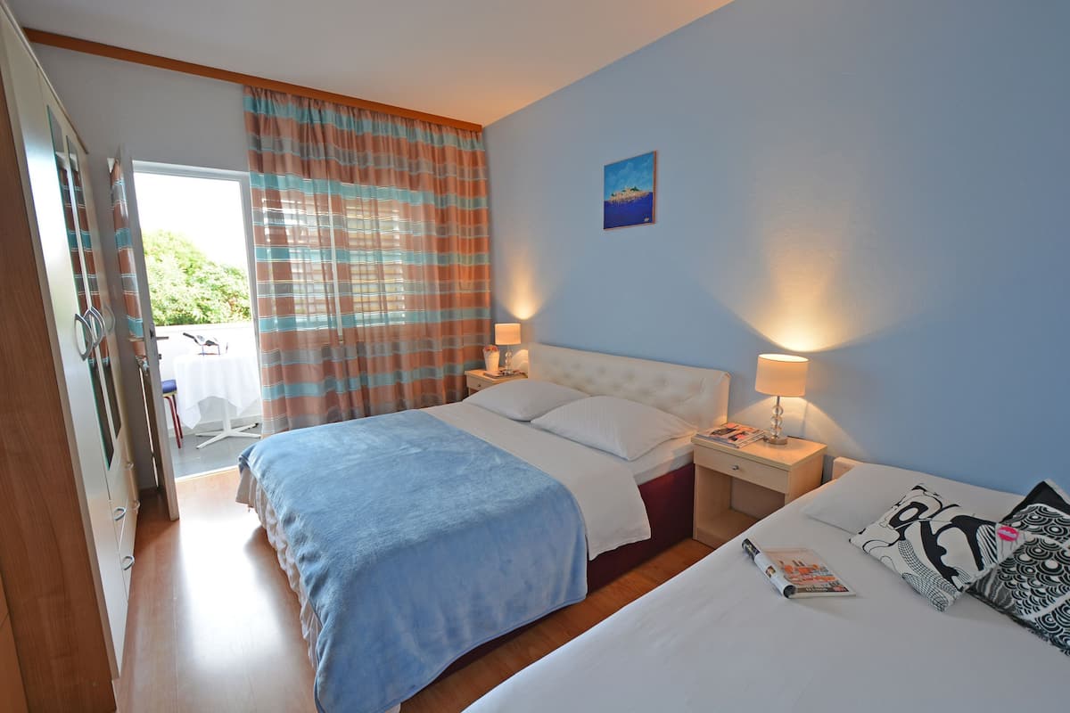 Hotelkamer met een bed, nachtkastjes, een raam met gordijnen, een schilderij aan de muur en uitzicht op groen.